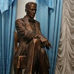 Памятник Булгакову - бронзовый писатель в половину натуральной величины восседает в подъезде дома № 10 по Большой Садовой